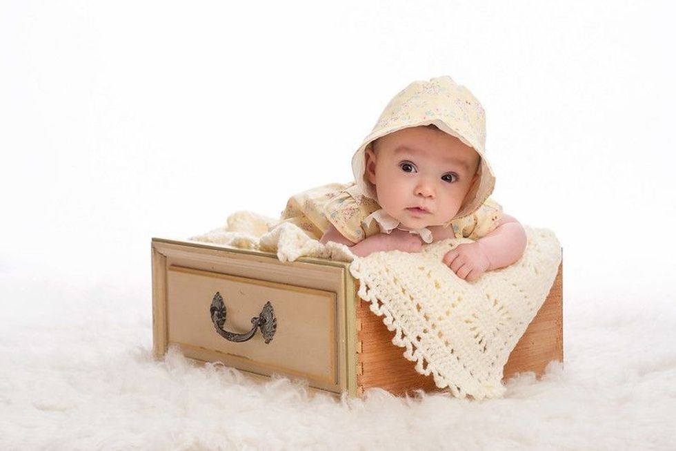 A 3 month old baby girl wearing a yellow bonnet