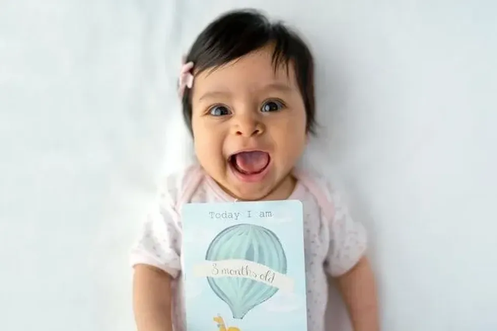 A baby girl lying on bed with a card