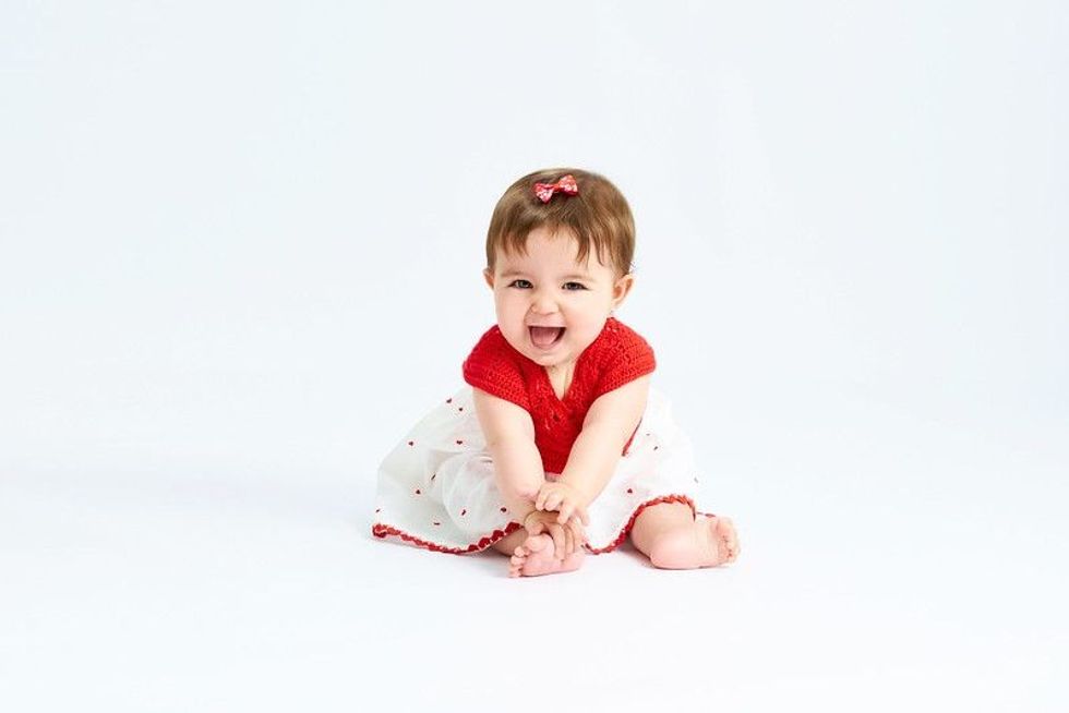 A baby of six months in a red dress