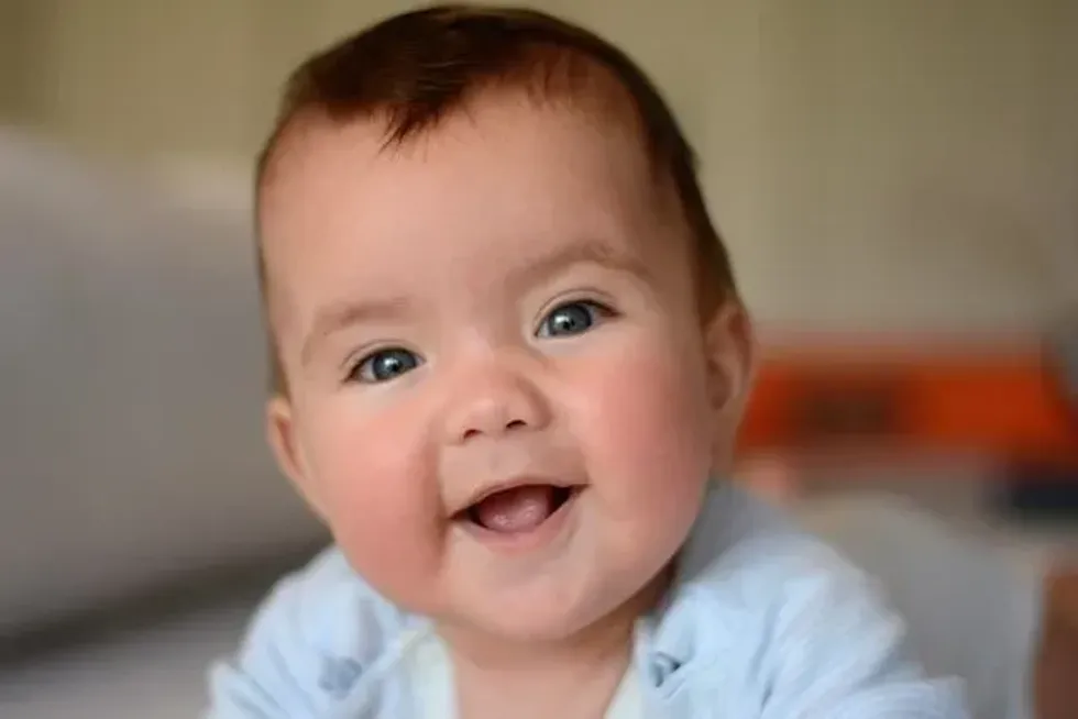 A cute baby with blue eyes smiling at the camera