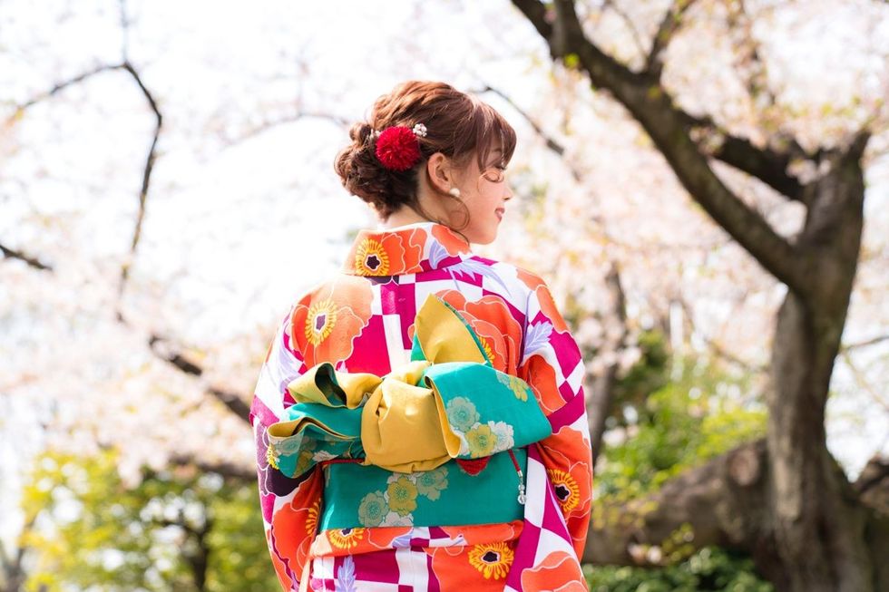 A girl dressed in traditional Japanese kimono, smiling with her back turned