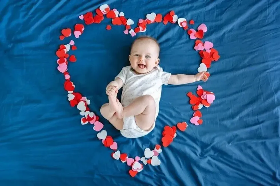 A happy newborn baby lying in middle of a heart