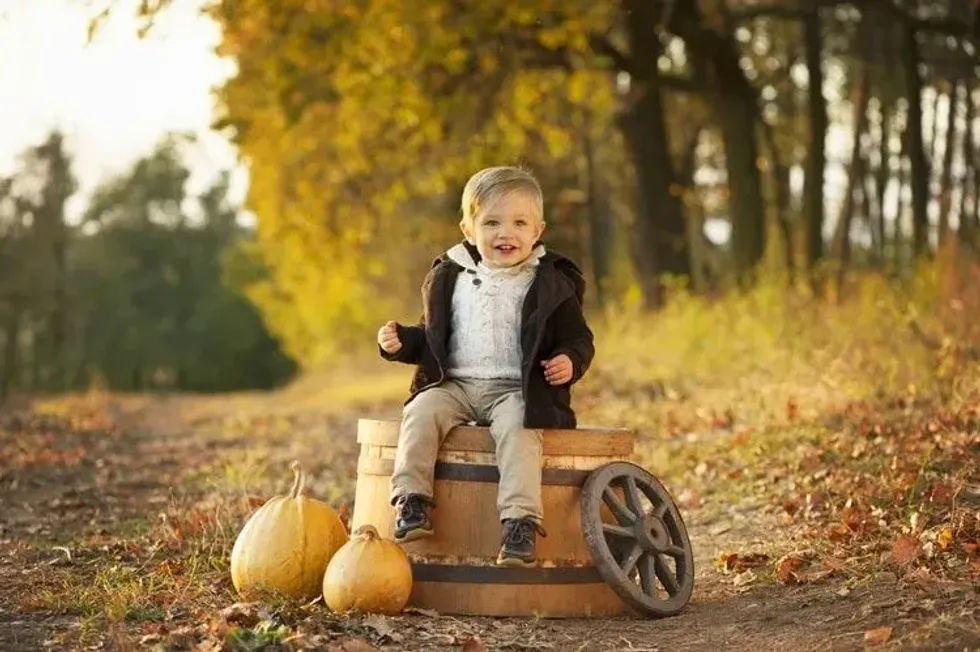 A little boy sitting on a barrel in a forest