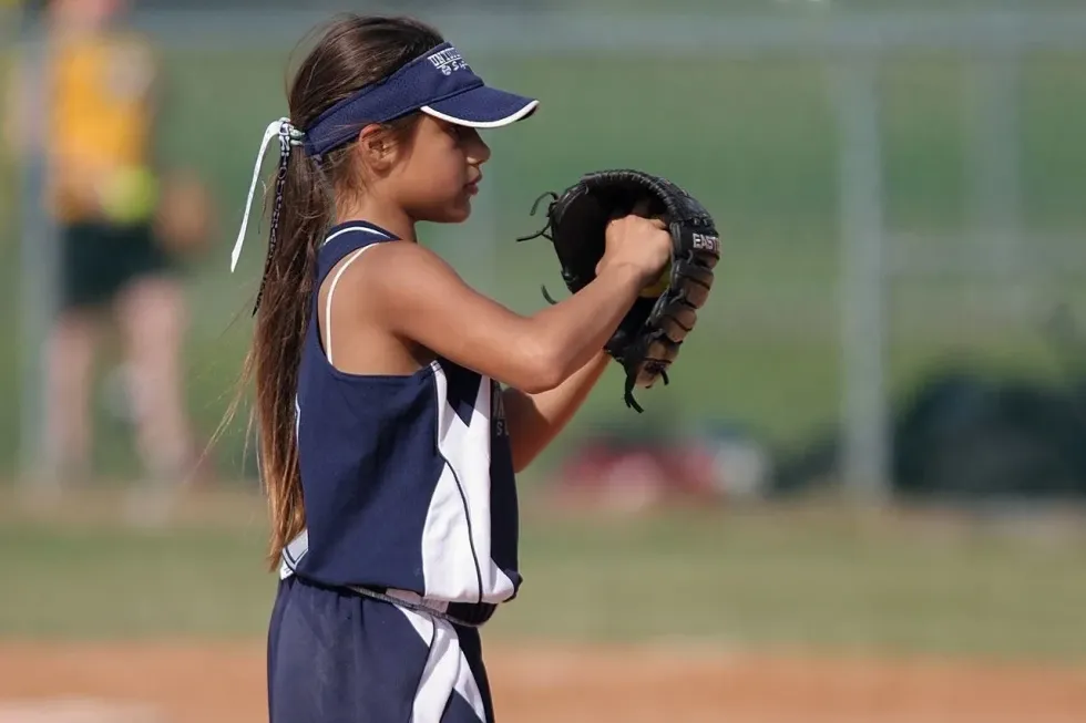 A little gir; playing baseball gloves ready to ball