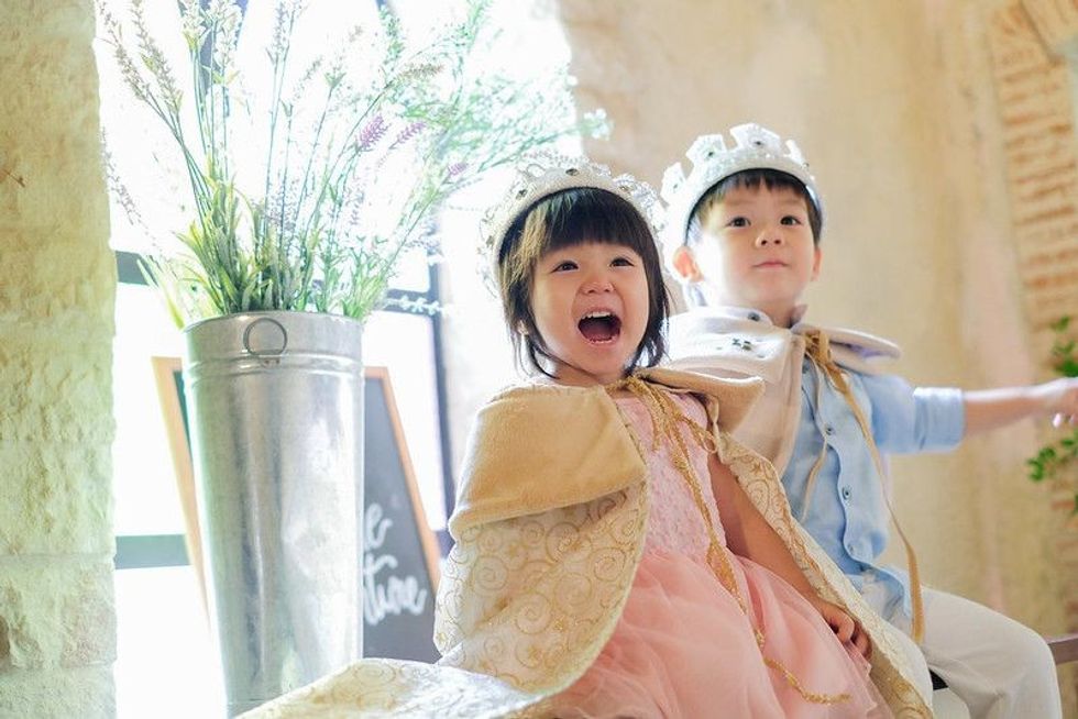 A little princess is smiling and sitting with a prince in a castle