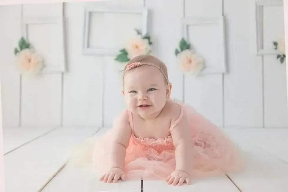 A newborn baby girl crawling on white floor