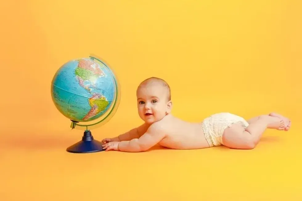 A newborn baby lying next to a globe