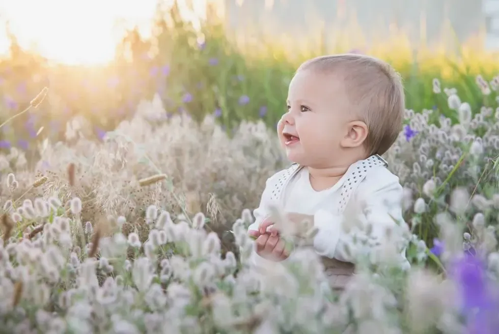 A newborn baby playing in the flower garden