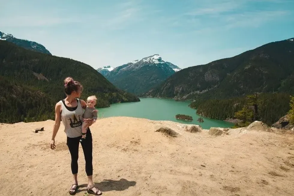 A woman holding her baby girl over the mountain with a beautiful view