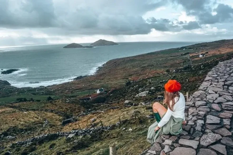 A woman sitting on rocks looking at the coastland