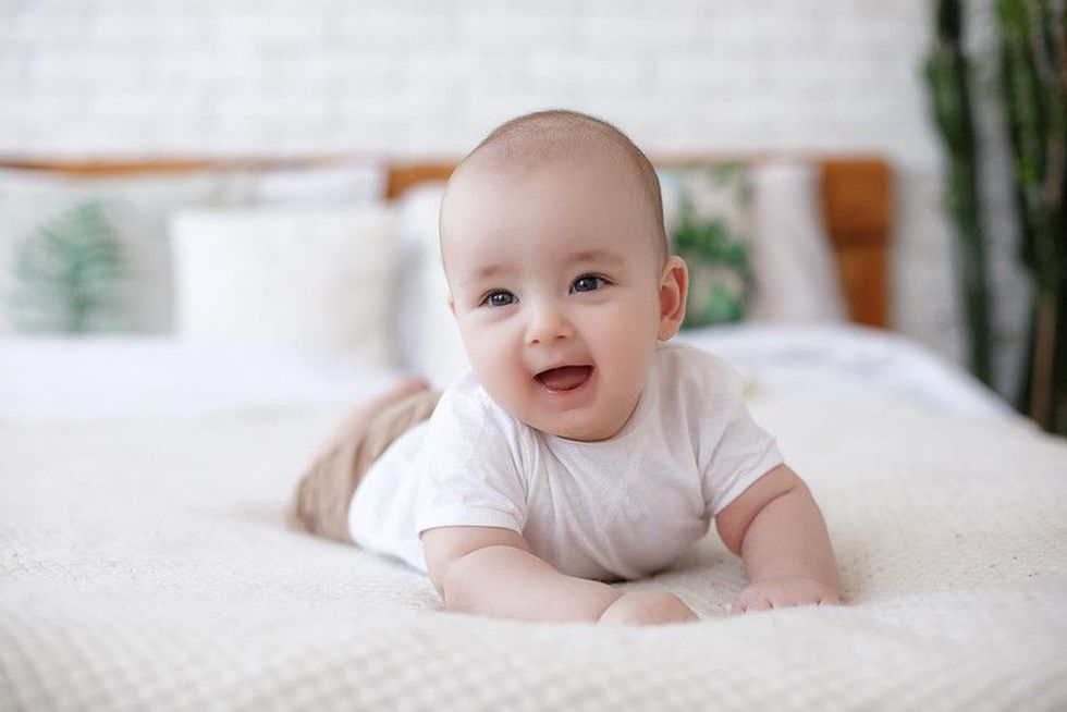 Adorable baby boy smiling on bed.