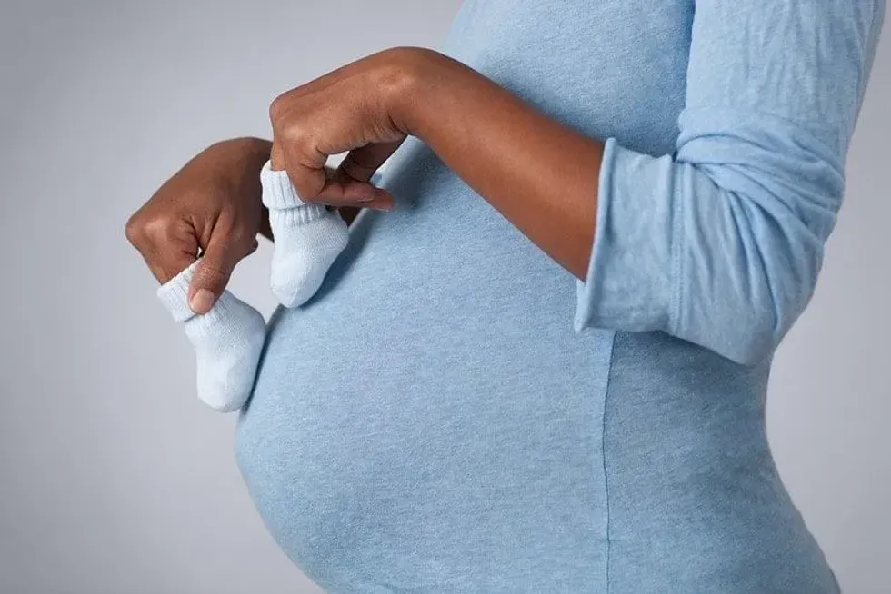 An expectant mother holding baby socks