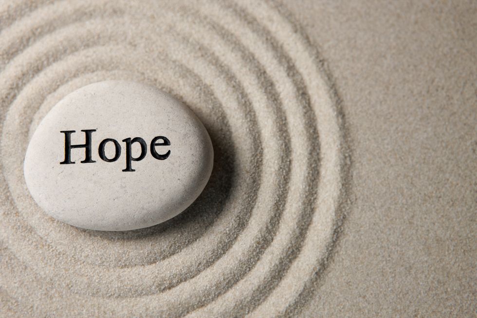 An image showing a pebble creating ripples on sand with the word Hope written on the pebble