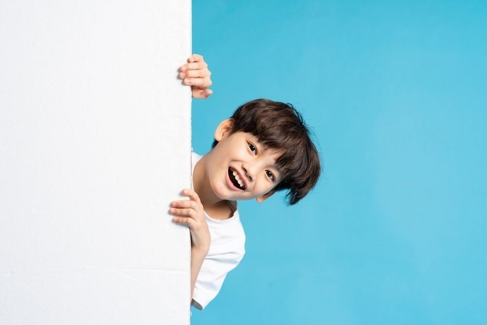 Asian boy peeking on blue background