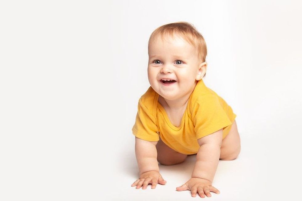 Baby boy child crawl on white studio floor.