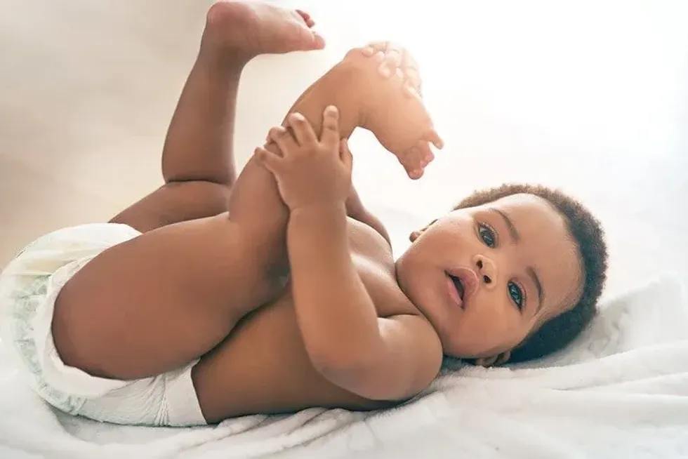 Baby boy lying on his back on the bed wearing a diaper.