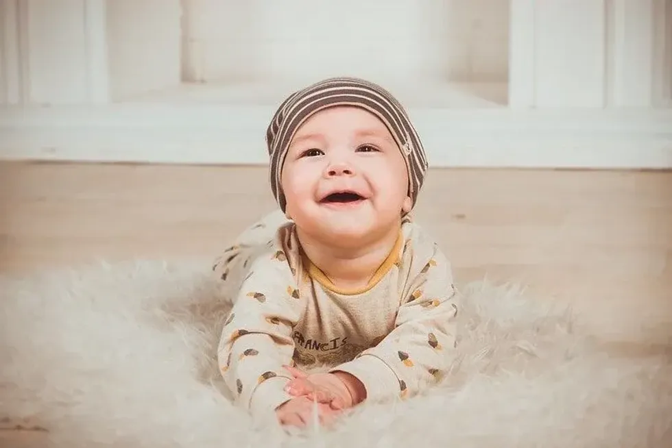 Baby boy lying on his tummy on a fluffy rug smiling.