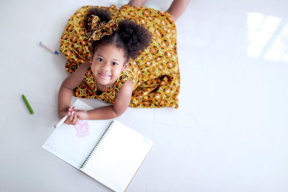 Baby girl with curly hair studying indoor