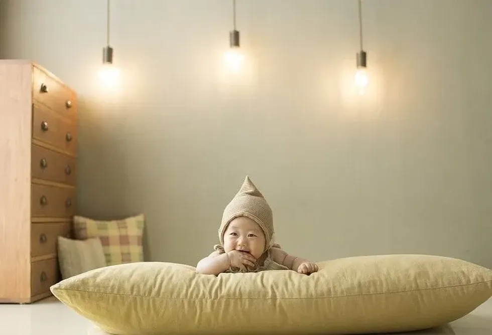 Baby lying on its tummy on a giant yellow cushion.