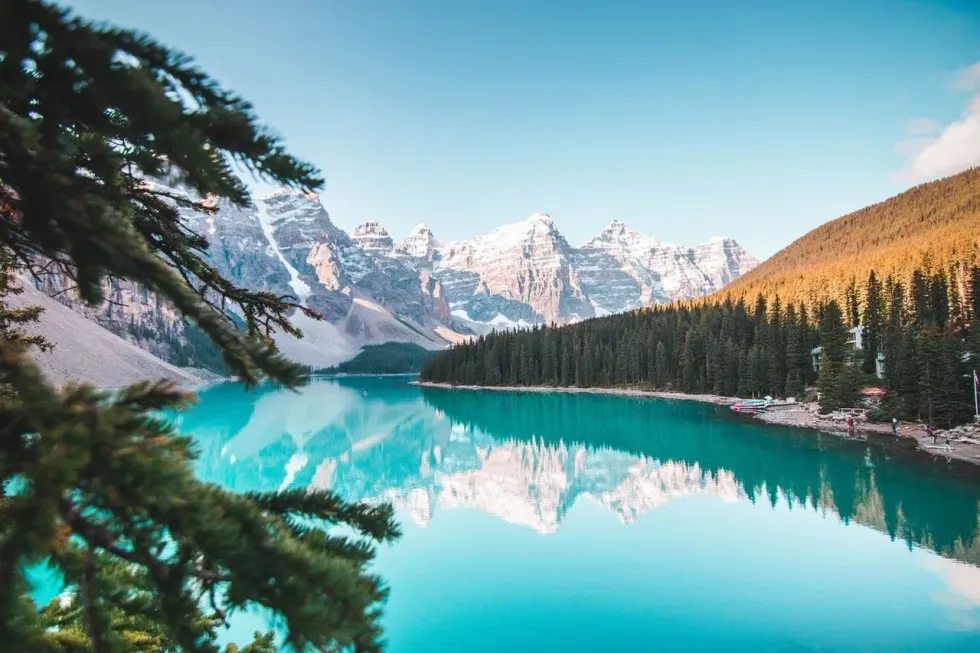 Beautiful landscape view of a blue lake, icy mountains, pine trees adorned in golden hour in Canada