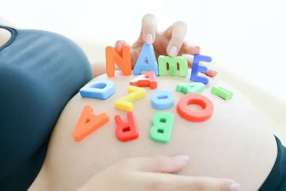 Colorful alphabets scattered on a woman's pregnant belly