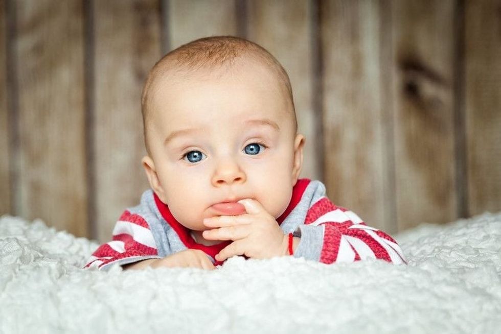 Cute 6 months old baby boy in a monkey costume lying on his stomach.