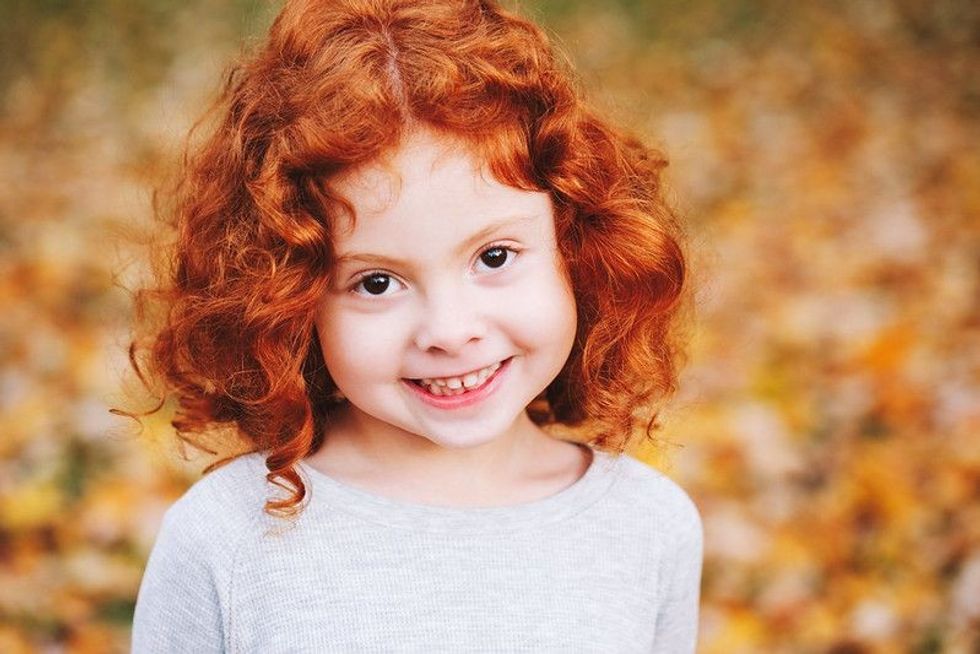 Cute adorable smiling little red-haired girl.