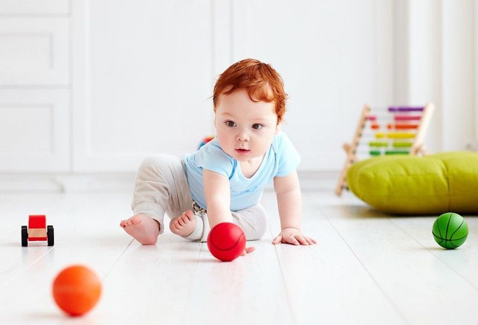 Cute infant baby crawling on the floor at home.