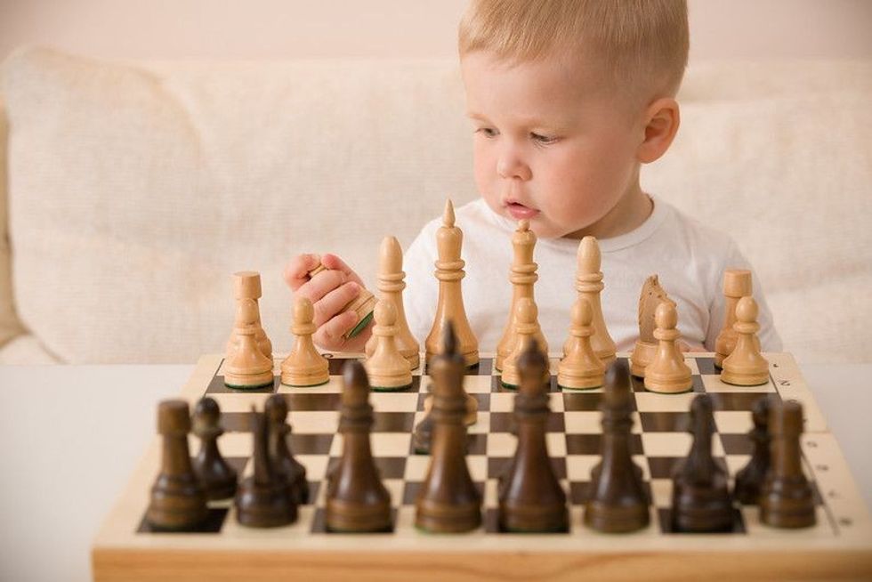 Cute little baby boy playing chess.