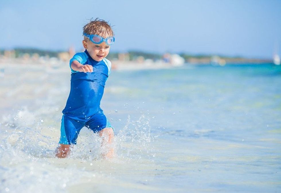 Cute little baby boy running in water on beach