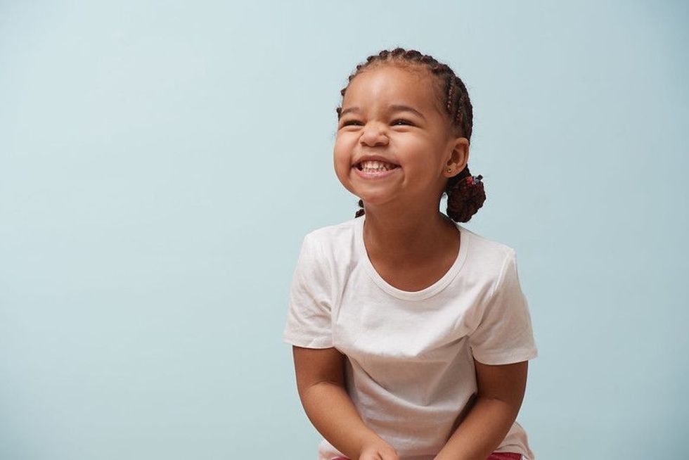 Cute little girl smiling and wearing braids.