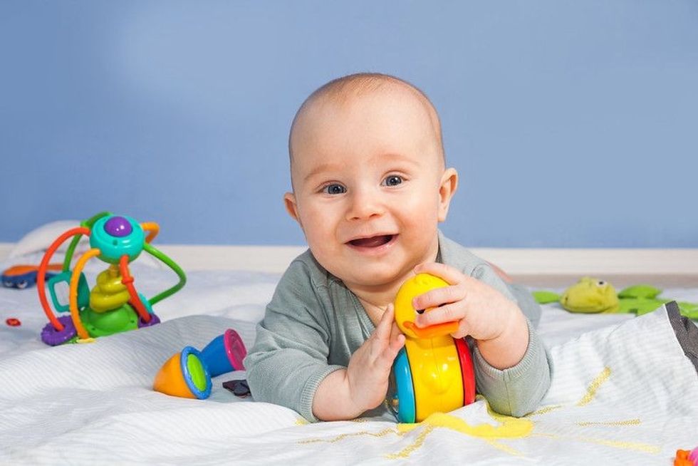 Five month old smiling baby with toys.