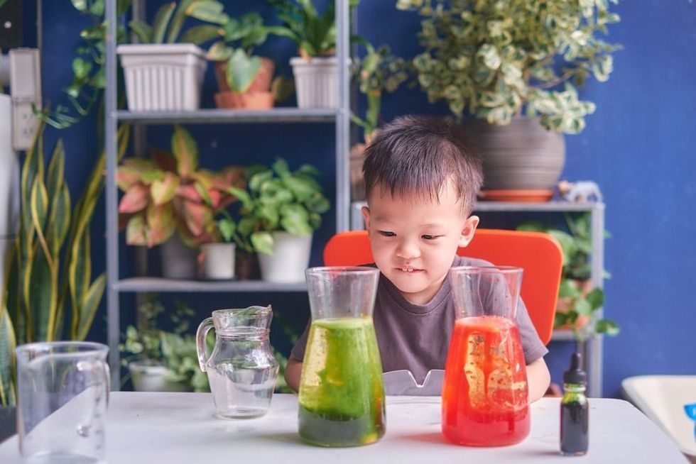 Happy little Asian school kid studying science, making DIY Lava Lamp Science Experiment with oil, water and food coloring.