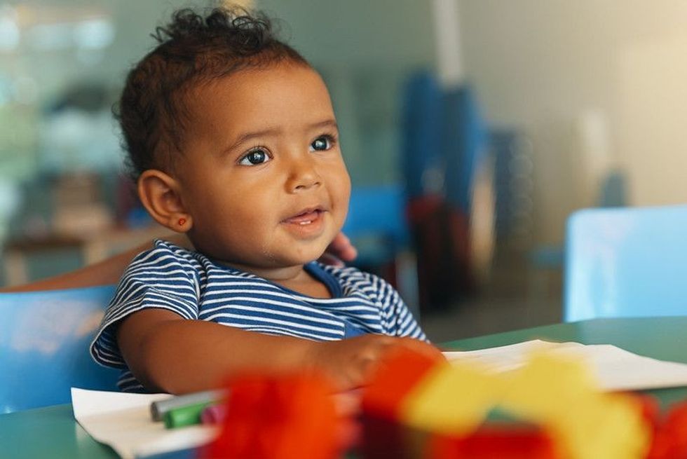 Happy newborn baby playing with crayons and blocks.