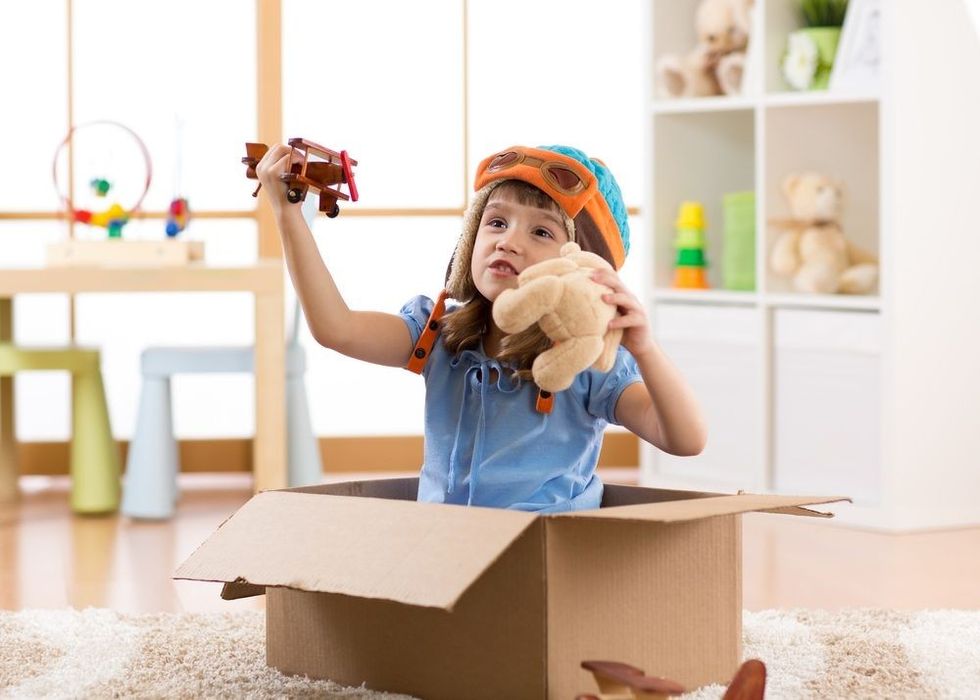 Kid pilot flying a cardboard box in kid room.