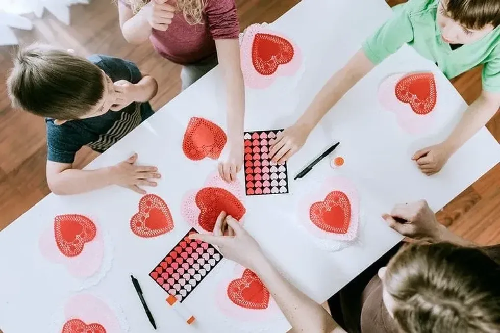 Kids learning craft with red hearts