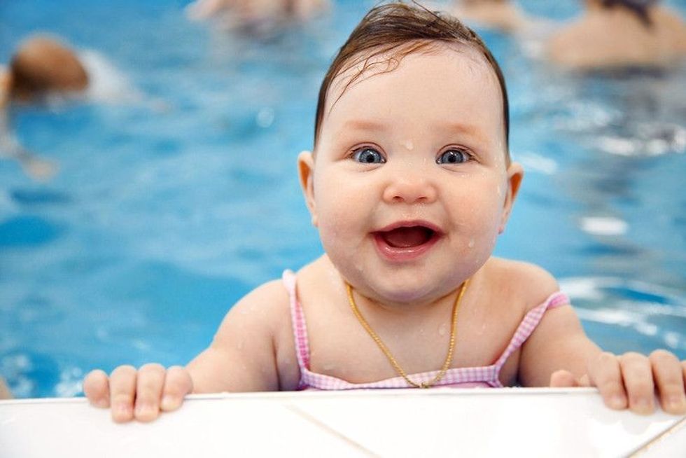 Little baby girl swimming in swimming pool