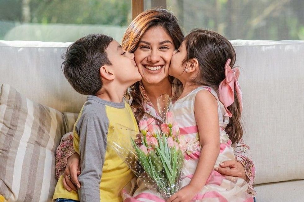 Little boy and girl kissing their mother