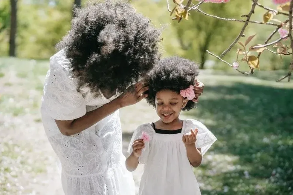 Mother putting a pink flower behind her daughter's ear