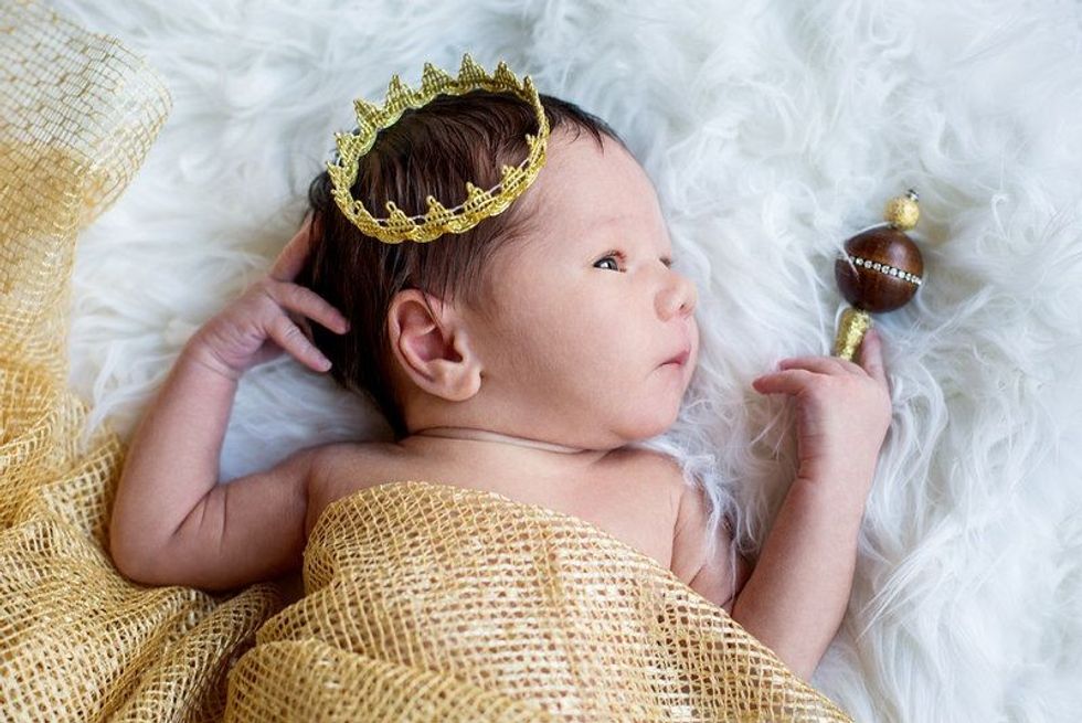 Portrait of a newborn baby boy wearing golden crown.