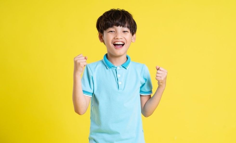 Portrait of an asian boy posing on a yellow background.