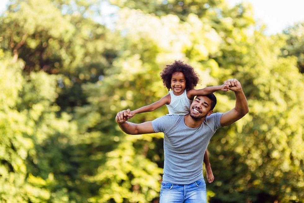 Portrait of young father carrying his daughter on his back.