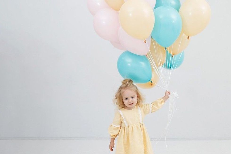 Pretty little girl holding pastel colored balloons