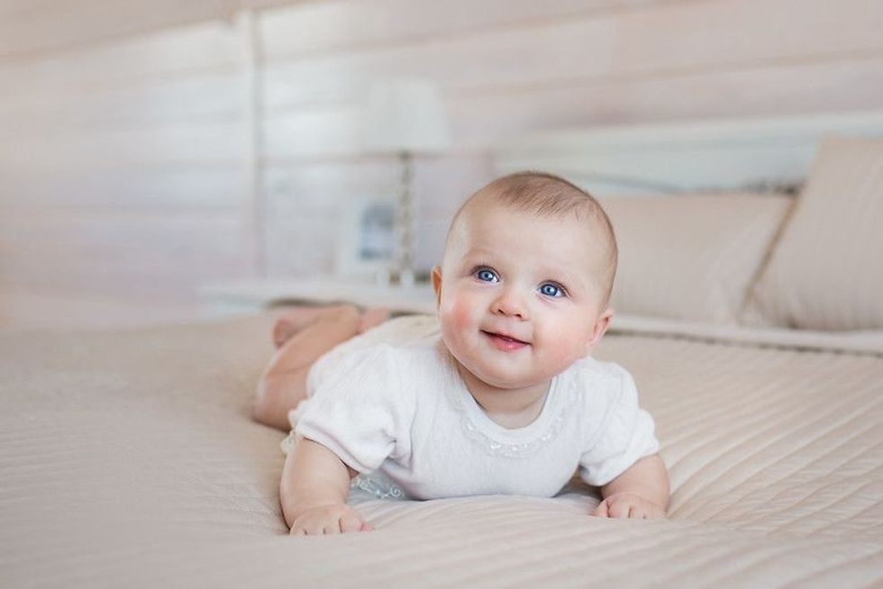 Pretty newborn lying and smiling on bed.