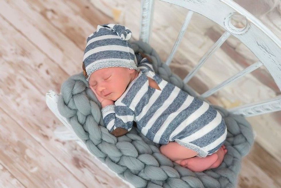 Sleeping newborn baby in basket wrapped in blanket in white fur background