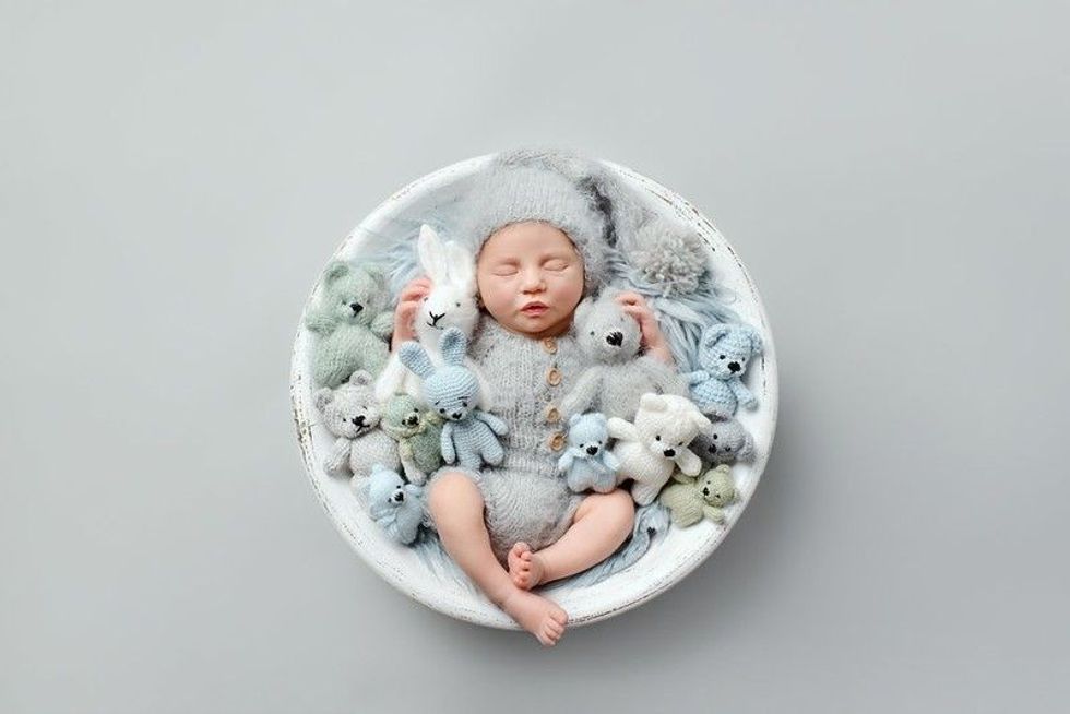 Sleeping newborn baby on a gray background with toys.