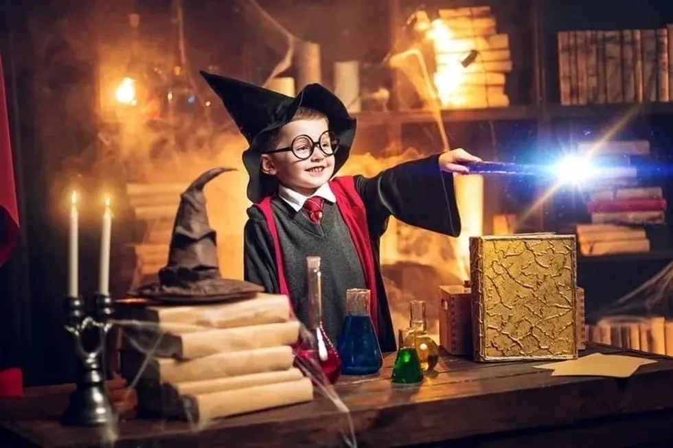 Small wizard in glasses and wizard's hat holding magic wand.