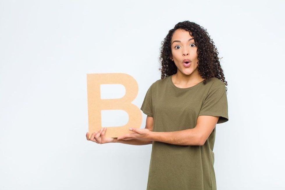 Surprised woman holding the letter B of the alphabet