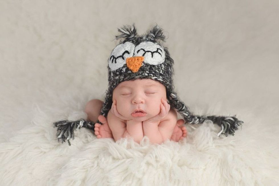 Three week old newborn baby boy wearing a crocheted owl hat.