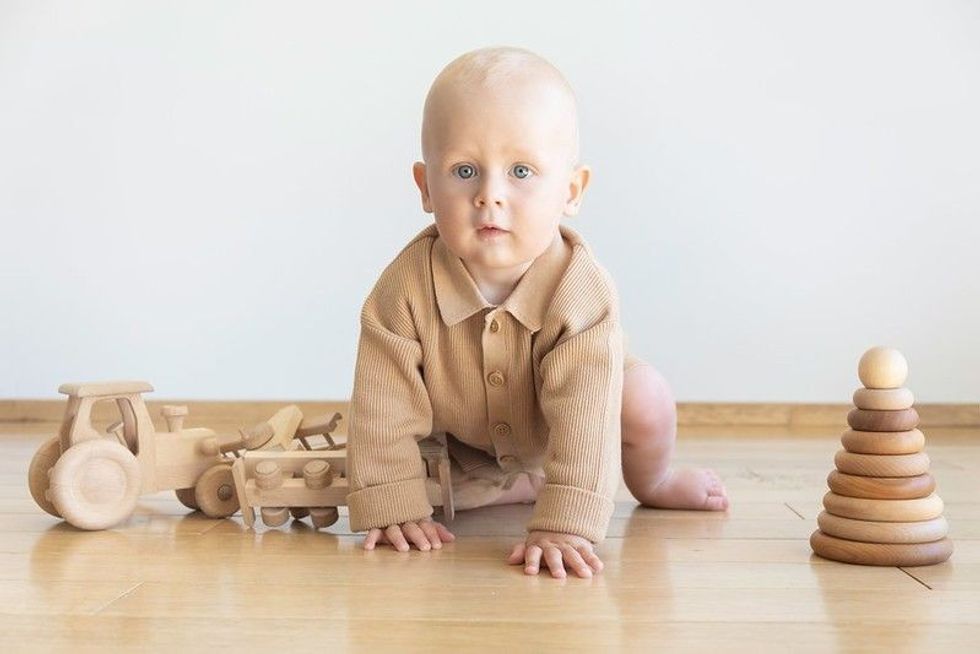 Toddler playing with wooden toys on floor.